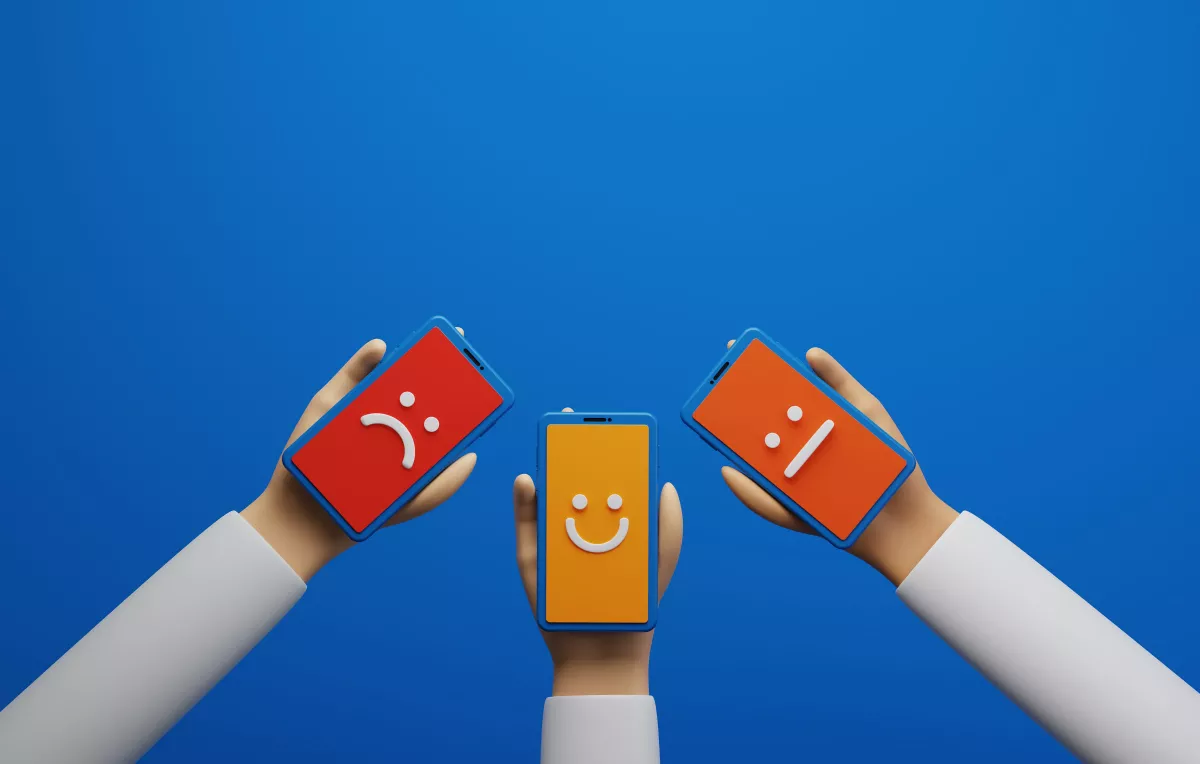 Three hands holding smartphones displaying emotions on their screens